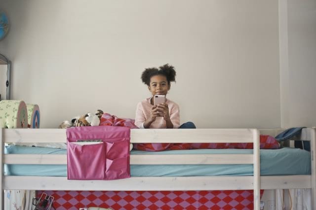 Kind auf Bett mit Handy