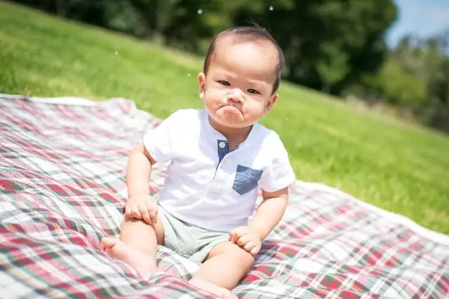 Kind sitzt auf einer Picknickdecke