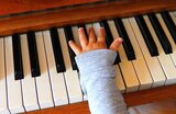Eine Kinderhand auf der Tastatur eines Klaviers