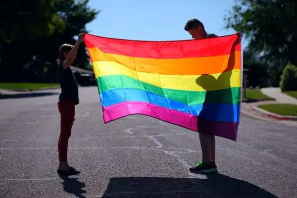 Zwei Menschen halten eine Regenbogen-Flagge