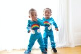 Zwei Kinder mit blauen Anzügen und Regenbögen auf den Anzügen 