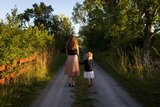 Frau und Kind laufen in der Natur nebeneinanderher 