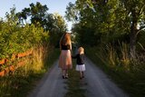 Frau und Kind laufen in der Natur nebeneinanderher 