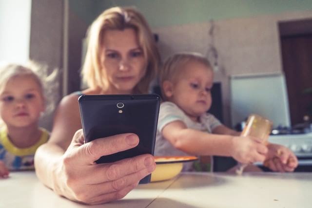 Frau mit Kindern und Telefon in der Hand