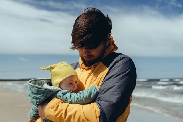 Erwachsener Mensch mit kleinem Baby im Arm in der frischen Luft