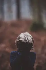 Kind draußen hält sich die Hand vor die Augen