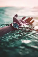Hand im Wasser mit Uhr am Handgelenk 