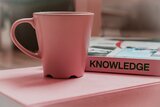 Tasse und Buch mit Aufschrift "Knowledge"