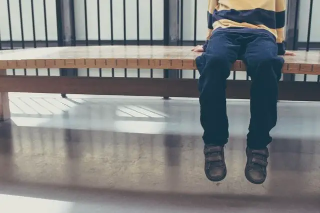 Kind sitzt auf einer Bank - nur Beine zu sehen