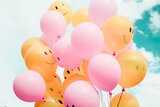 Luftballons in orangener und rosa Farbe mit lächelnden Smileys 