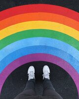 Zwei Füße vor einem aufgemalten Regenbogen auf dem Boden 