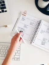 Hand mit Stift vor einem vollen Kalender